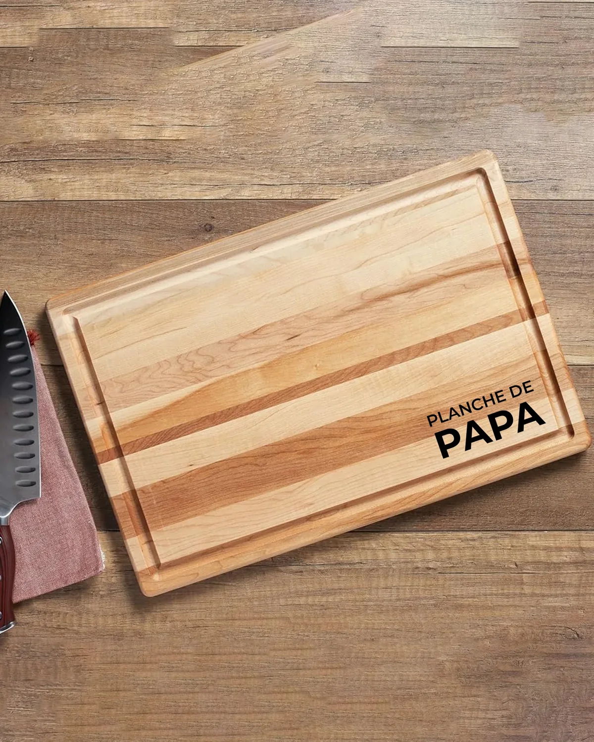 Planche à découper en bois gravée « Planche de papa », posée sur une table près d’un couteau de chef